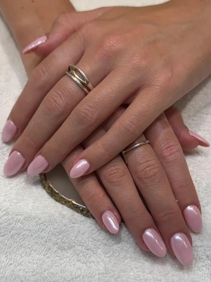 Gros plan dune manucure BIAB rose chatoyant dans un salon