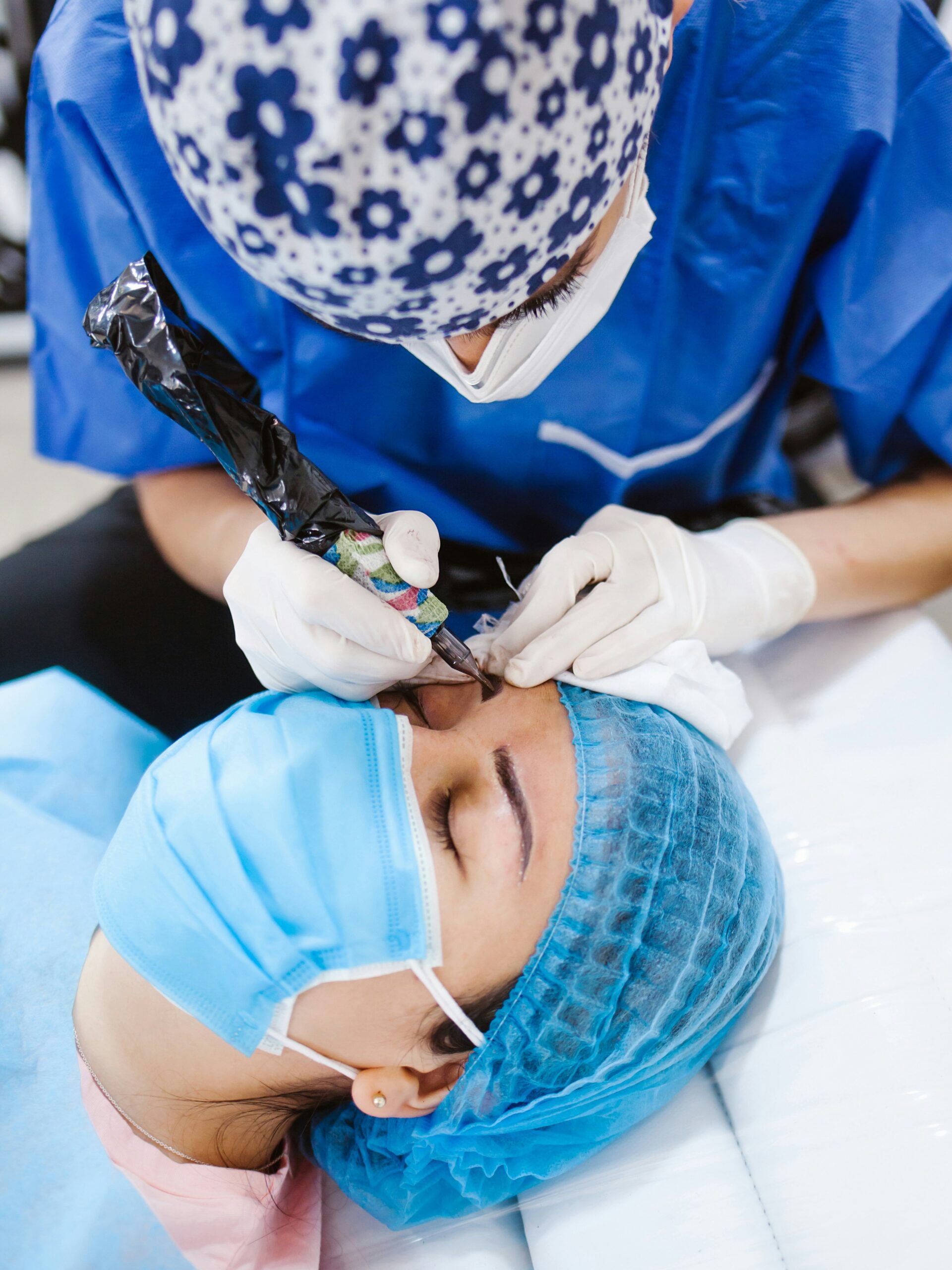 Gros plan sur une femme recevant un microblading, allongée sur une table de soin et portant un masque