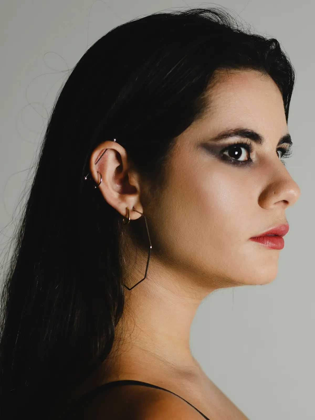 Photo en studio d'une femme portant une barre industrielle ainsi que des piercings au lobe et à l'hélix