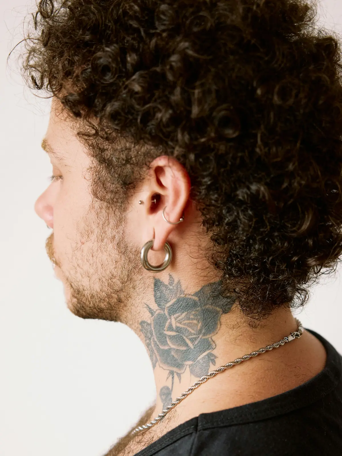 Photo de dos d'un homme portant des piercings au lobe, à l'hélix et au tragus