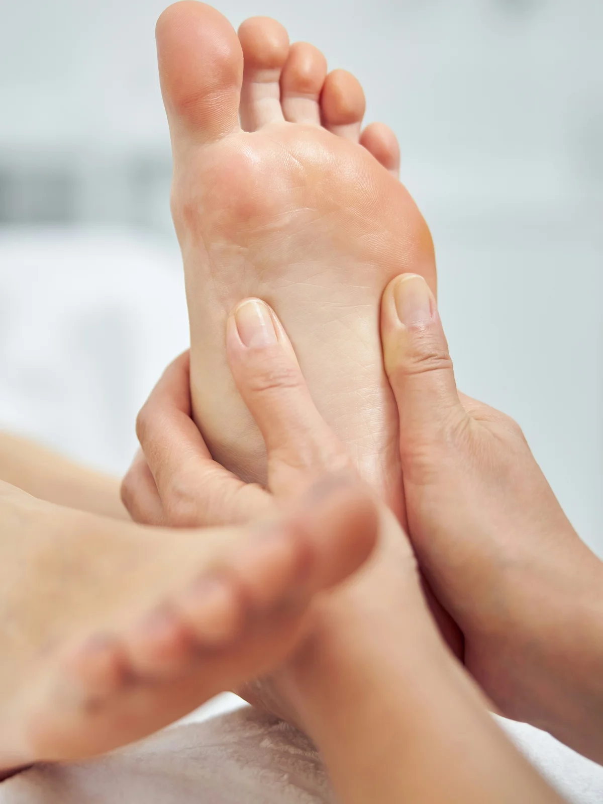 Gros plan sur une esthéticienne qui masse le pied d'une cliente pendant une beauté des pieds à sec