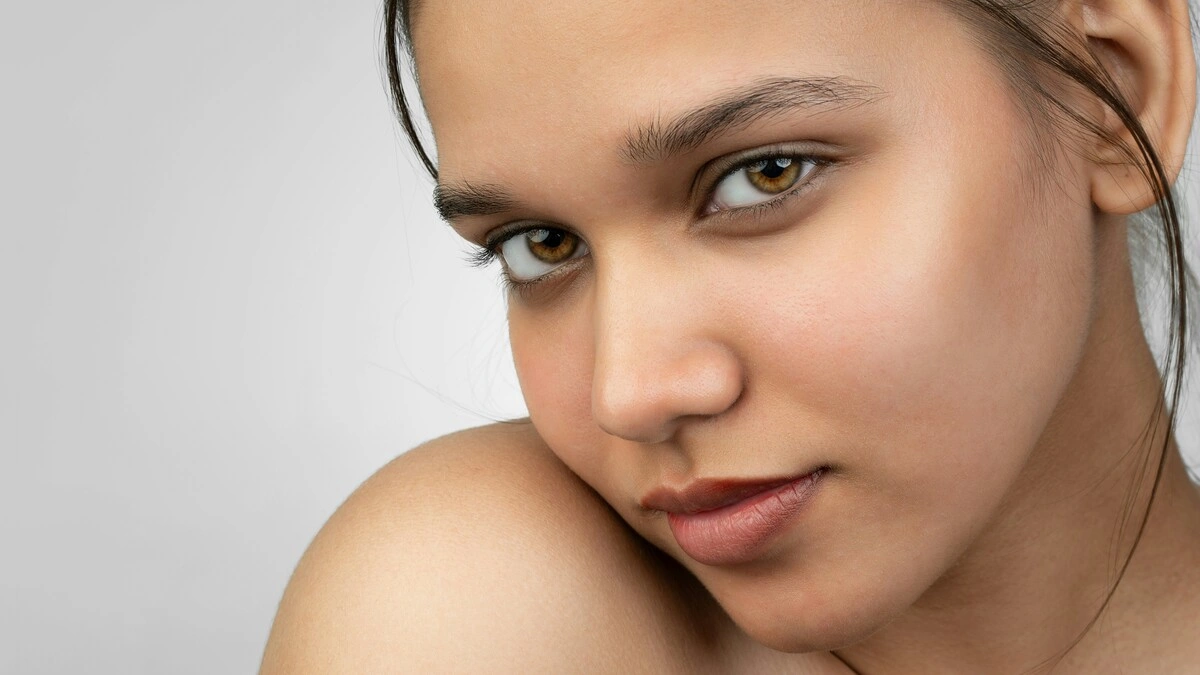 Gros plan d'une femme souriant à la caméra, montrant sa peau lisse et sans maquillage