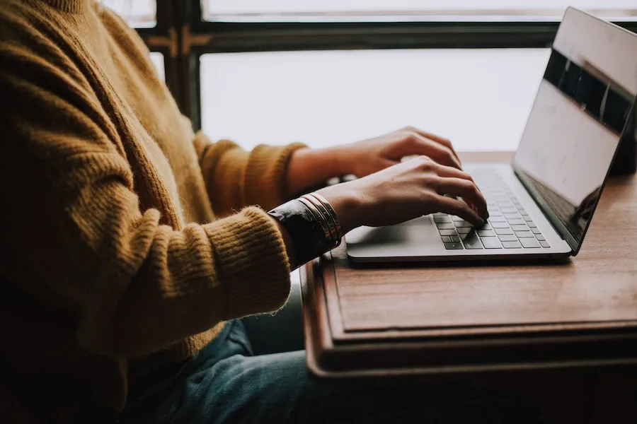 Una titolare di salone seduta a un tavolo, mentre lavora al computer portatile per gestire la parte amministrativa.