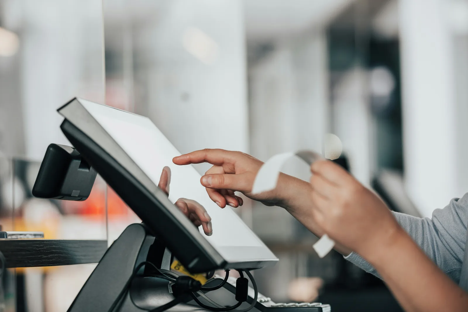 Mani usano un sistema di cassa touchscreen al banco e staccano uno scontrino stampato
