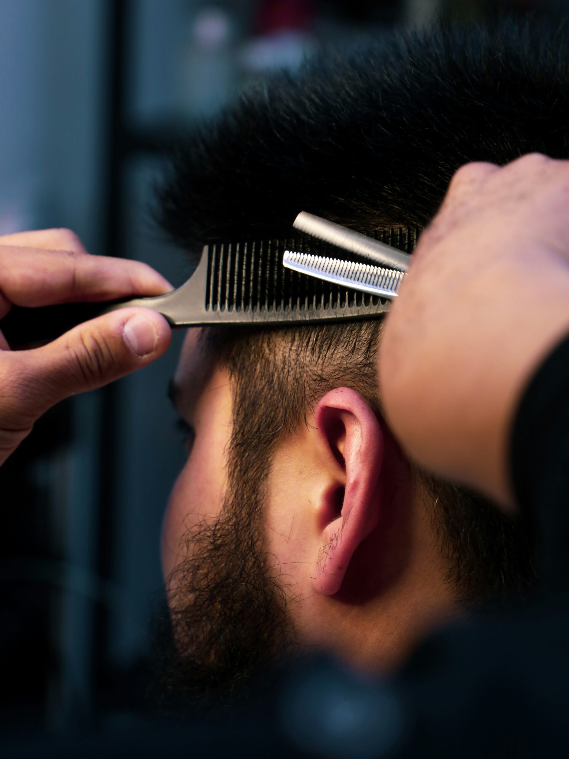 Primo piano di un barbiere che esegue un taglio mullet su un cliente, sfumando con cura i lati.