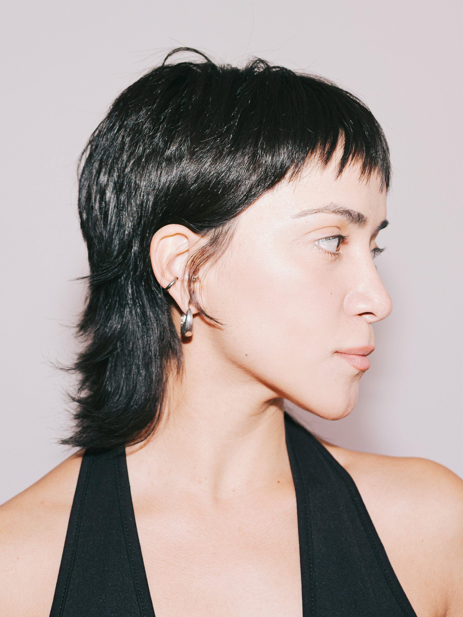Una giovane donna con un mullet liscio e top nero con scollo all'americana.