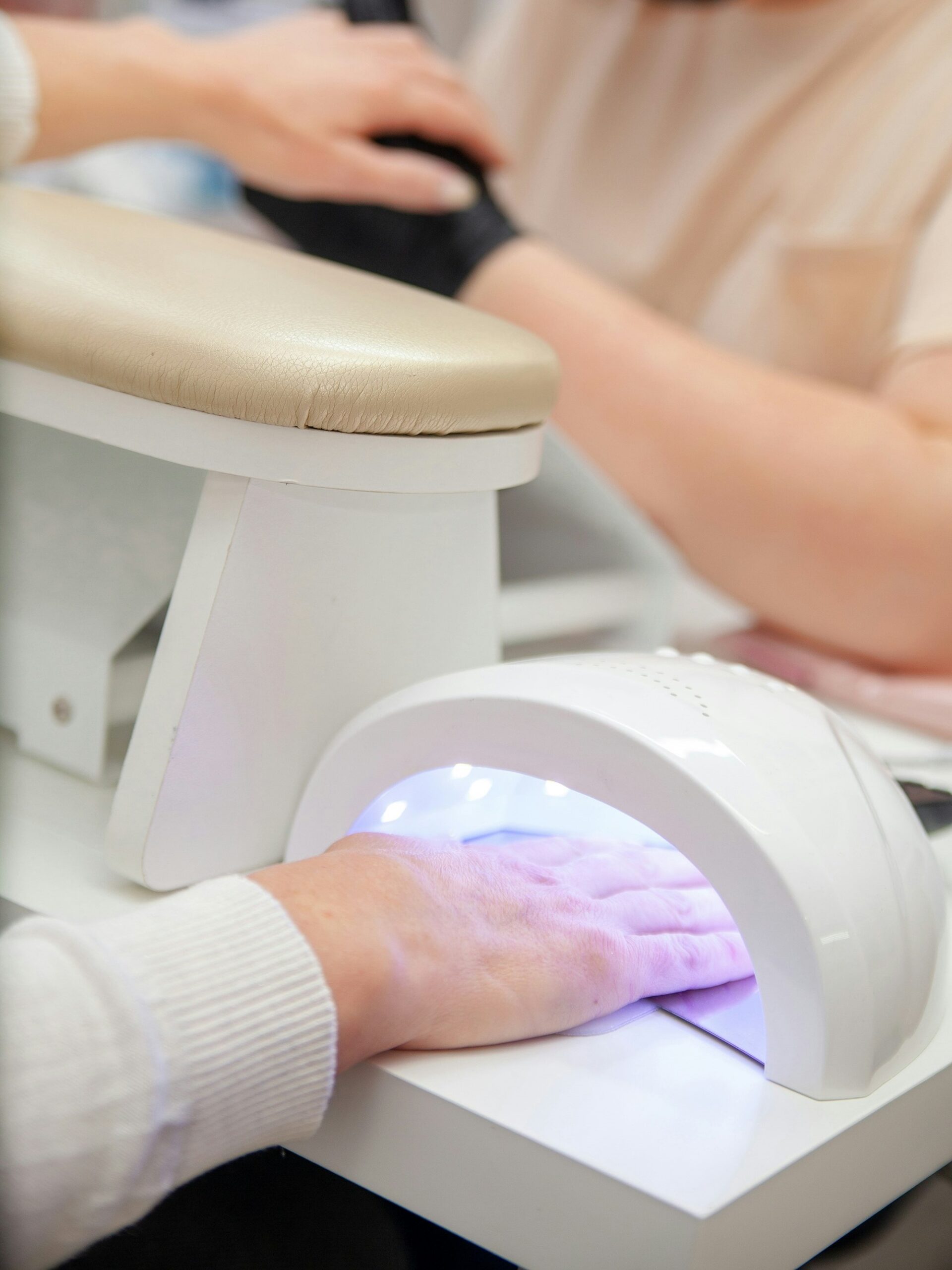 Una cliente in un salone di bellezza polimerizza la manicure BIAB sotto una lampada UV