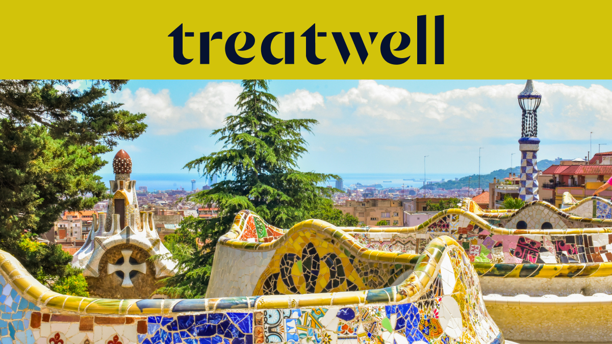 Una vista panoramica di Barcellona dal Park Güell, con le iconiche panchine in mosaico colorato di Gaudí e le guglie fiabesche in primo piano, la città e il mare sullo sfondo. Un banner giallo in alto mostra il logo "treatwell".