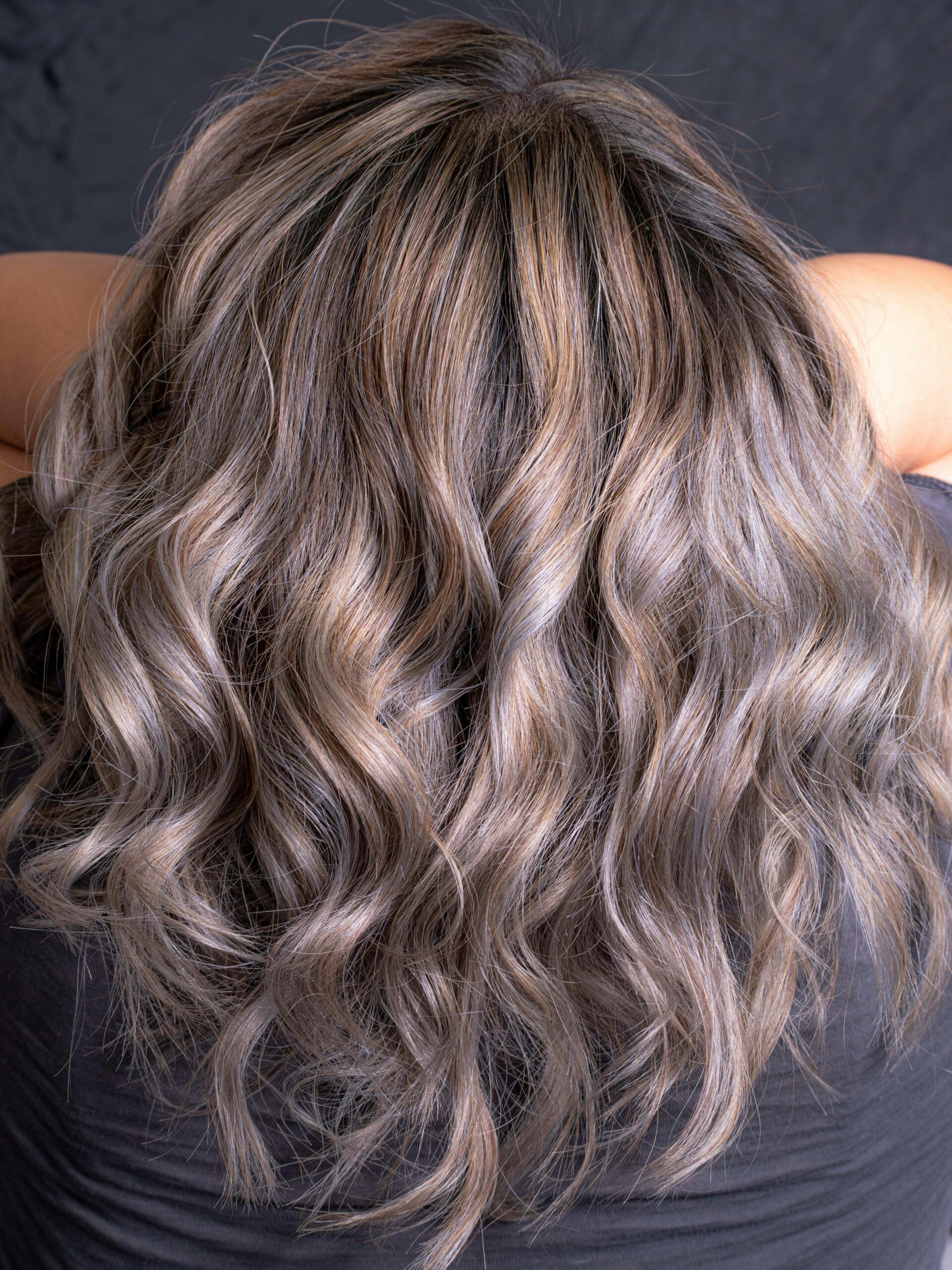 Nuca di una donna con capelli mossi e sfumature grigie sfumate