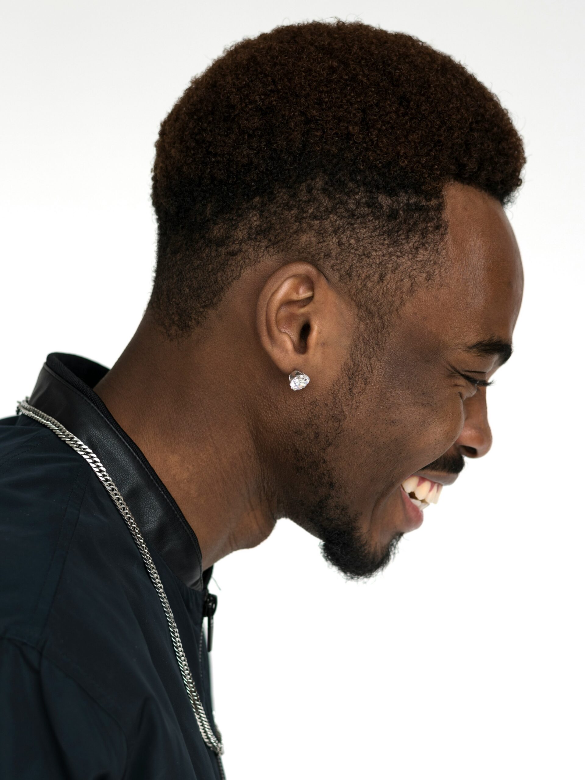 Profilo laterale di un uomo sorridente con capelli afro e un taper fade alto
