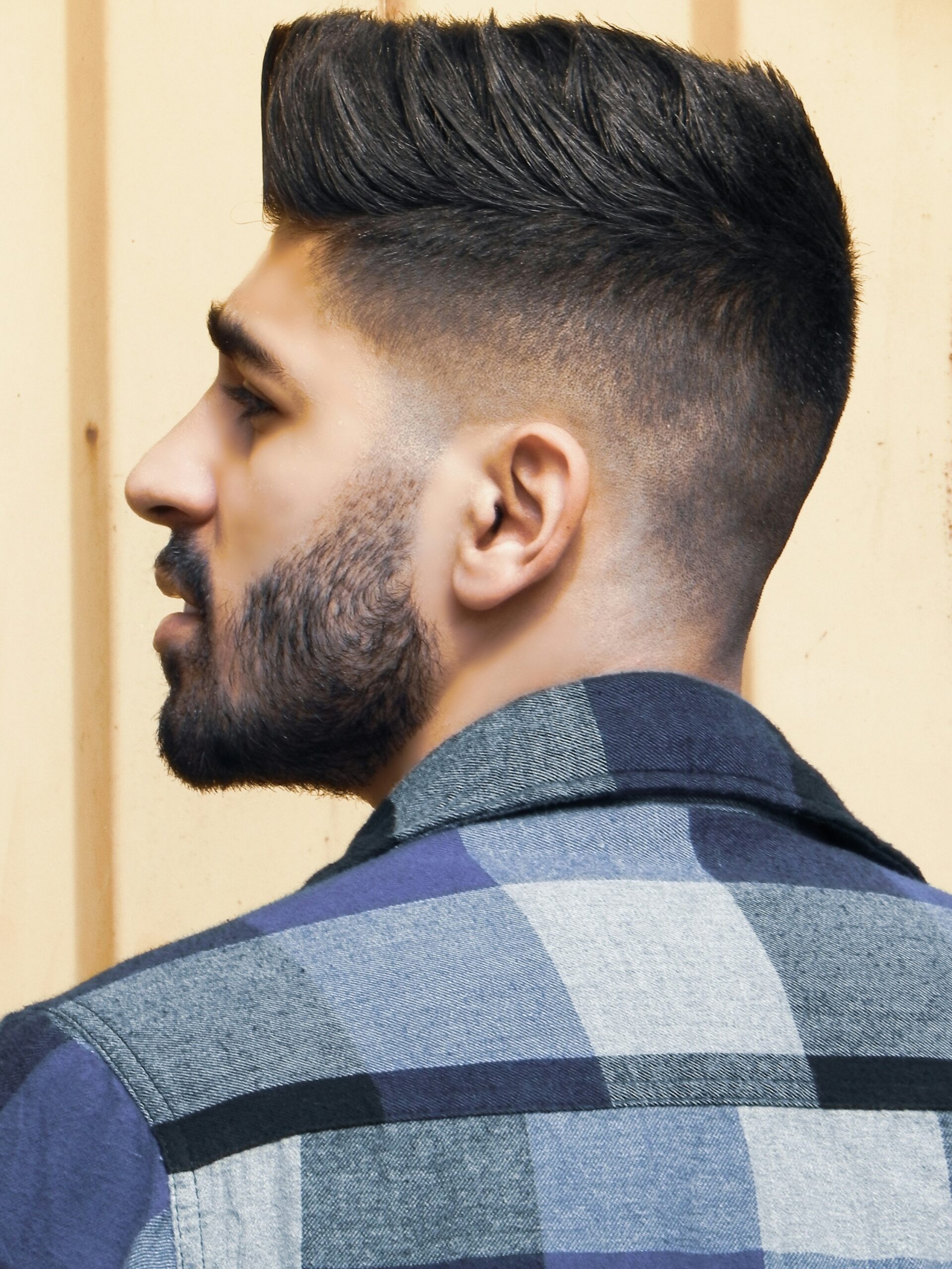 Ritratto di profilo di un uomo con un'acconciatura faux hawk abbinata a un taper fade alto