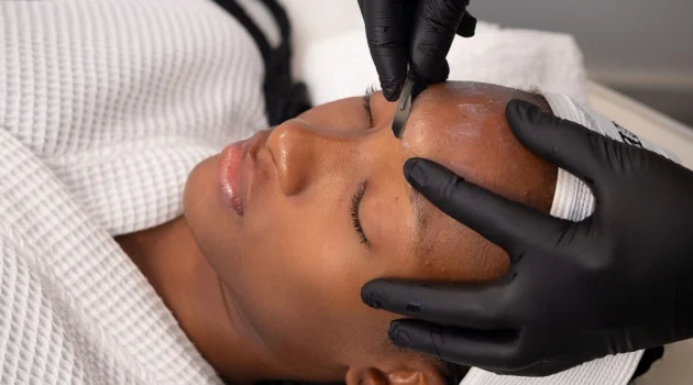 Primo piano di un'estetista che esegue il dermaplaning su una cliente in un centro estetico