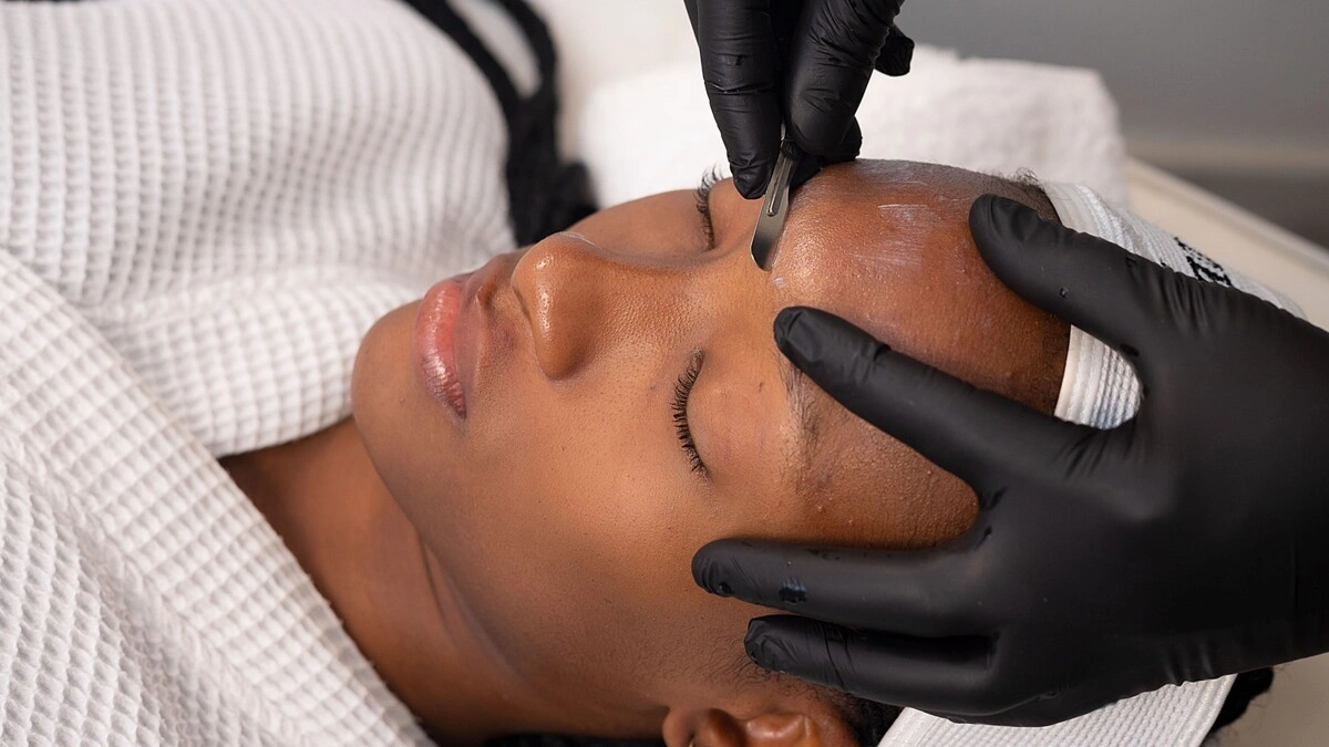 Primo piano di un'estetista che esegue il dermaplaning su una cliente in un centro estetico