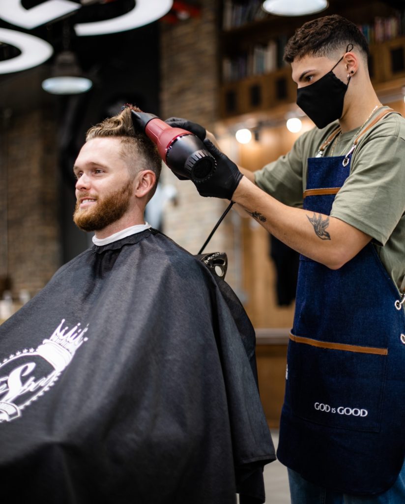 Ein Mann bekommt seine Haare in einem Barbershop geföhnt.