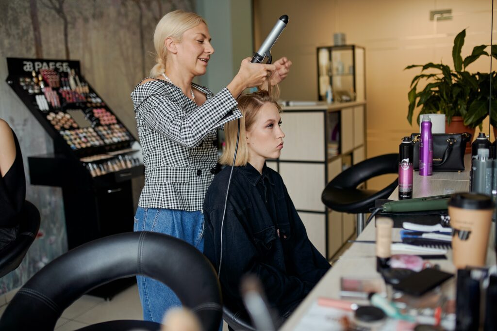 Eine Coiffeurin lockt einer Kundin die Haare