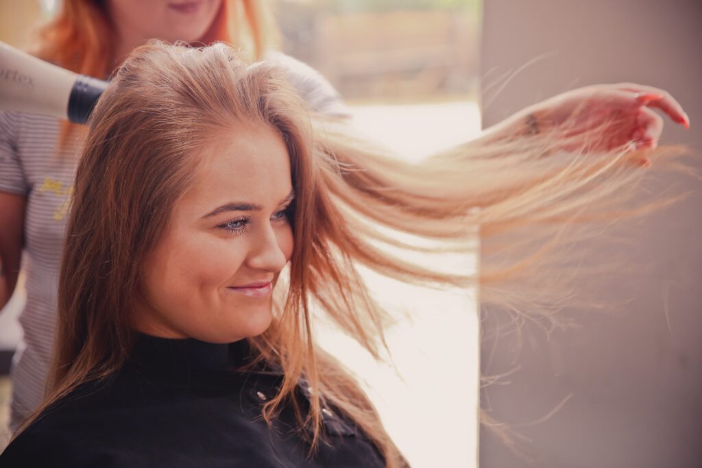 Eine Coiffeurin föhnt einer Kundin die Haare