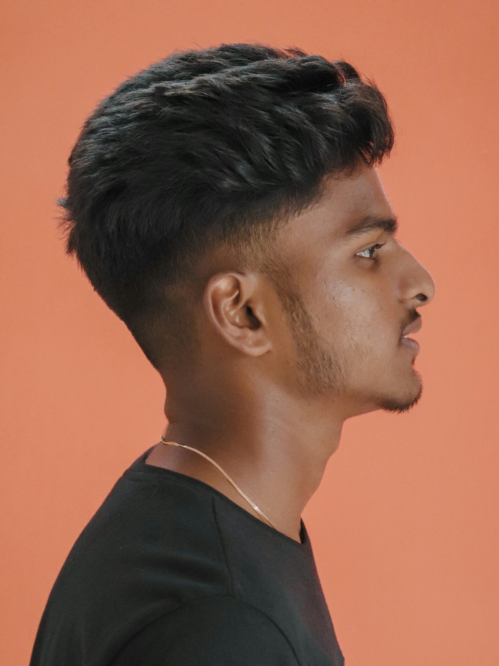 Seitenporträt eines Mannes mit texturiertem, voluminösem Haar und einem Low Taper Fade