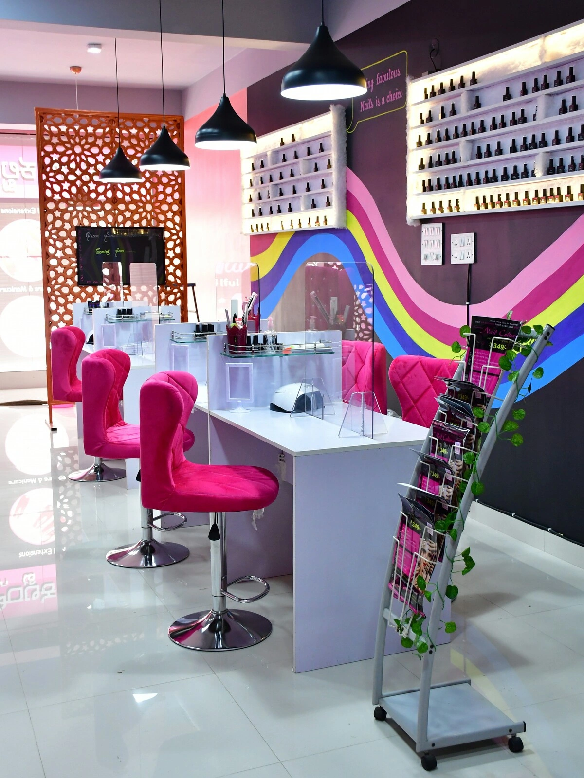 Innenraum eines Nagelstudios mit sauberen weissen Tischen, rosa Samtstühlen und einer violetten Wand