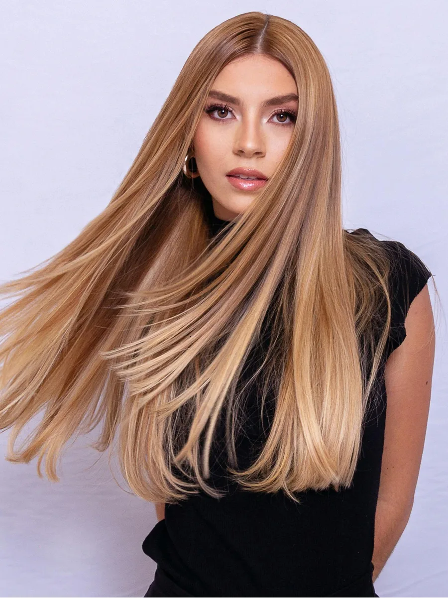 Studioporträt einer Frau, die ihr langes, glänzendes karamellblondes Haar schwingt