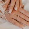 Klassische weisse French-Tip-Maniküre auf naturbelassenen, eckig gefeilten Nägeln auf weissem Stoff