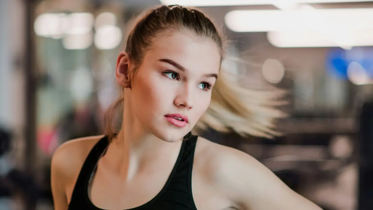 Eine junge Frau im Sporttop bewegt sich zur Seite, während ihr Pferdeschwanz nach aussen schwingt
