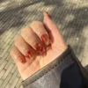 Lava-Nail-Art mit bernsteinfarbenen und roten Wirbeln auf transparenter Basis
