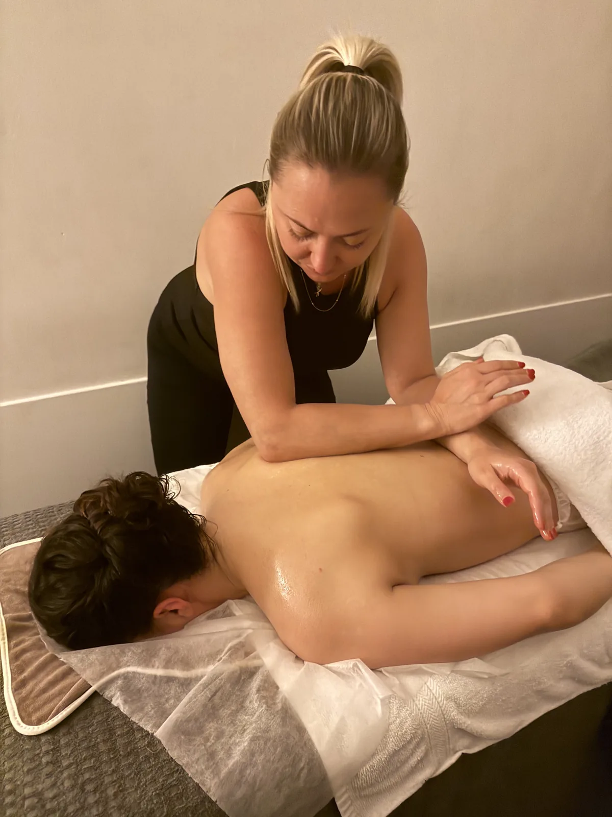 Therapeutin bei einer Rückenmassage auf der Behandlungsliege